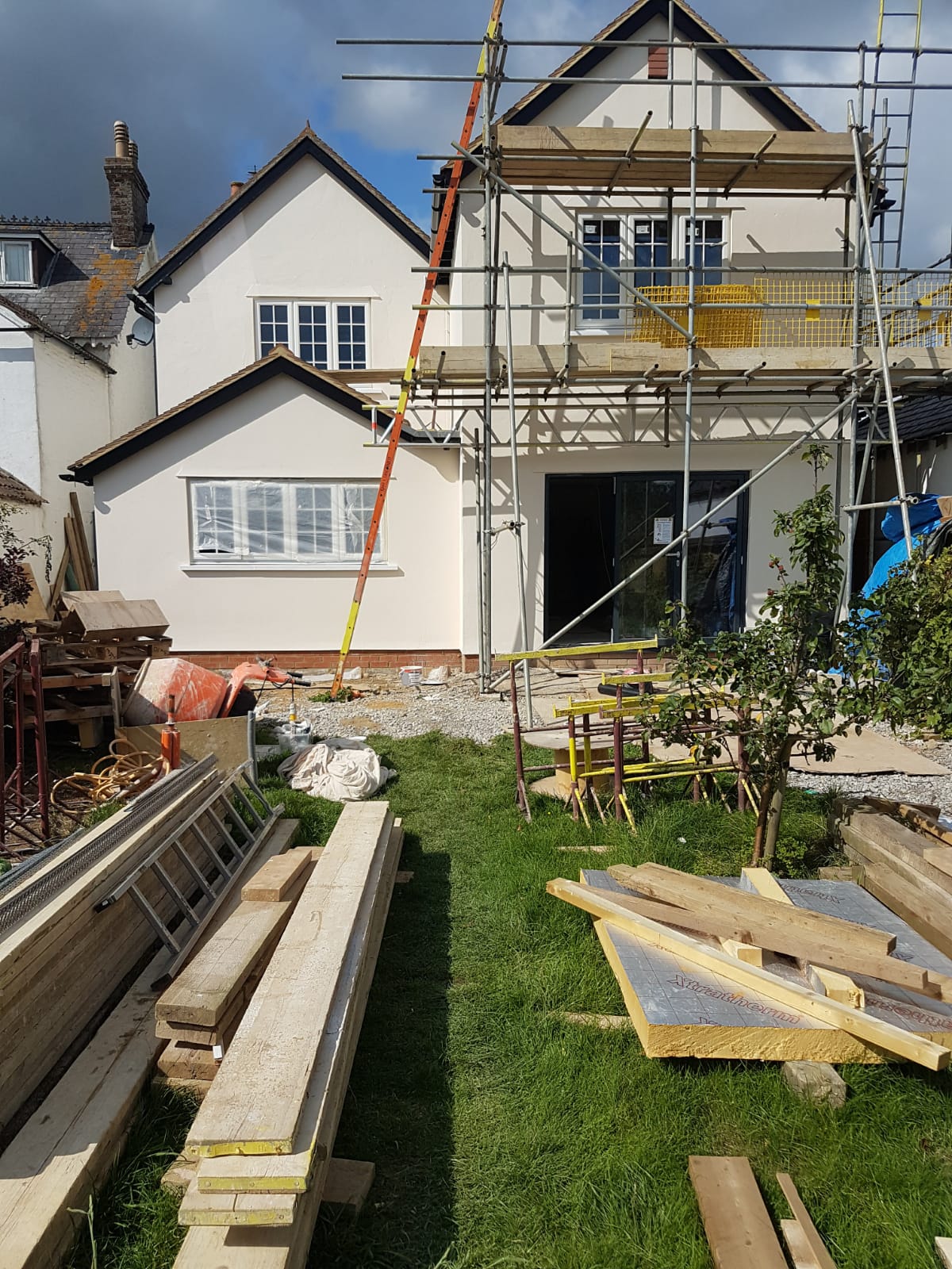 A house under construction with scaffolding and wood.