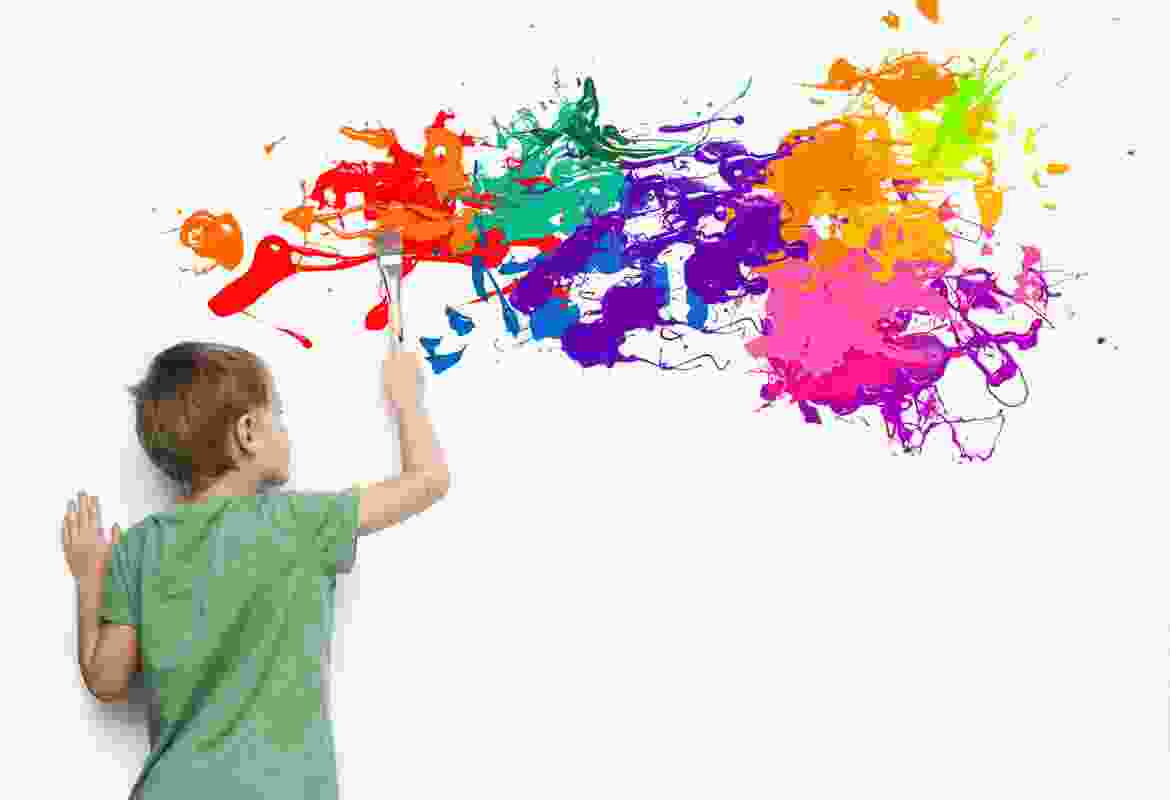 A boy is painting a wall with paint splatters.