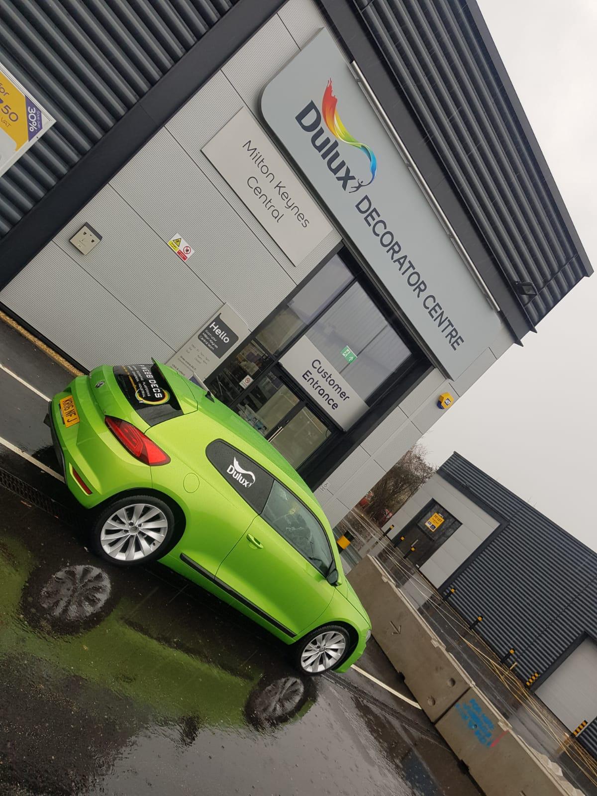 A green volkswagen cabrio parked in front of a building.