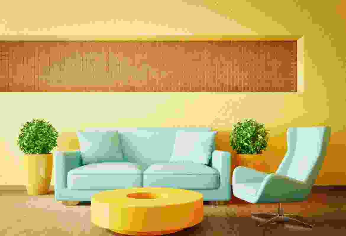 A living room with a blue couch and a yellow wall.