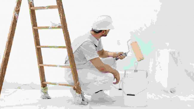 A man painting a white room with a ladder.
