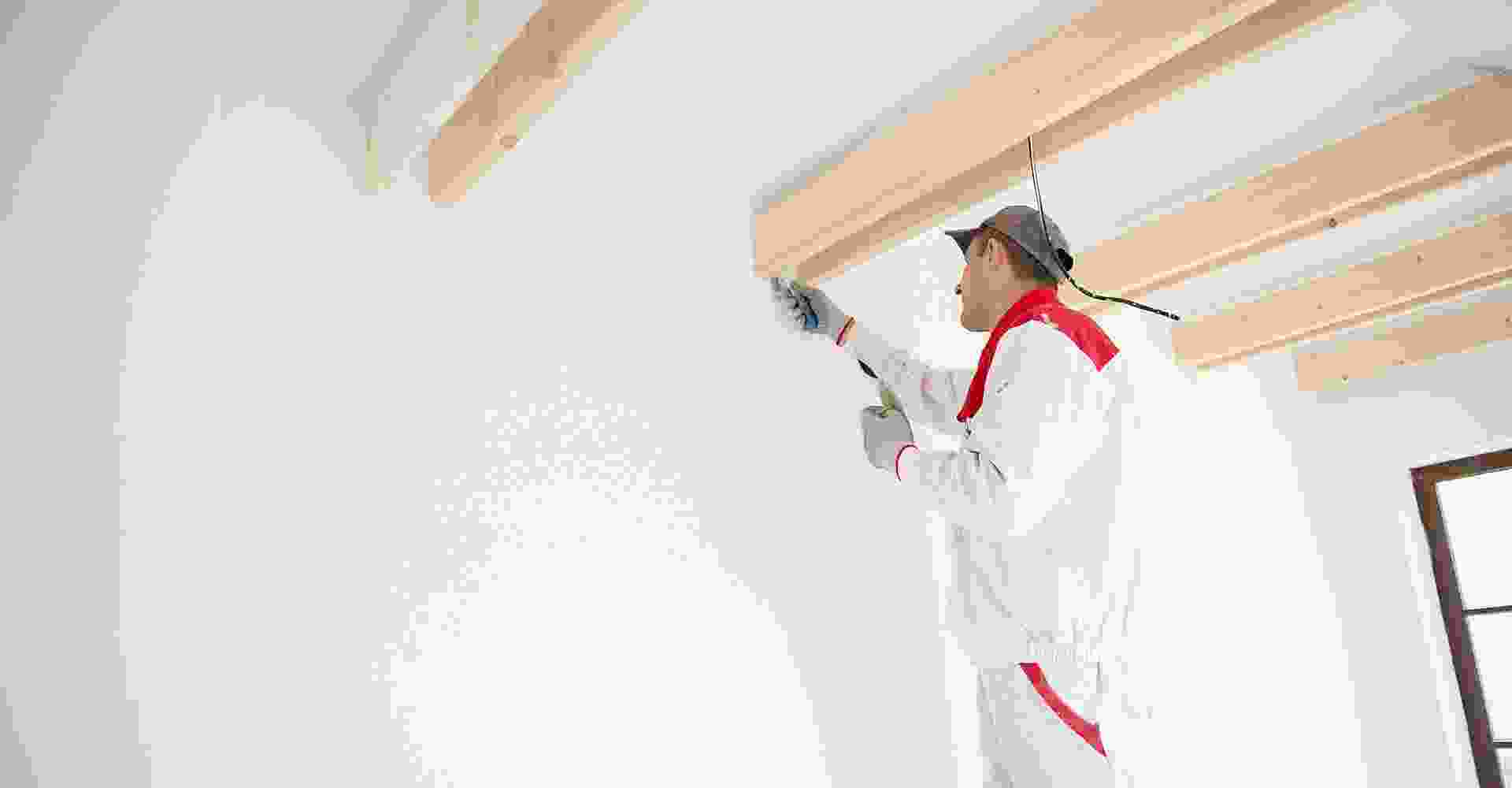 A man is painting the ceiling of a room.