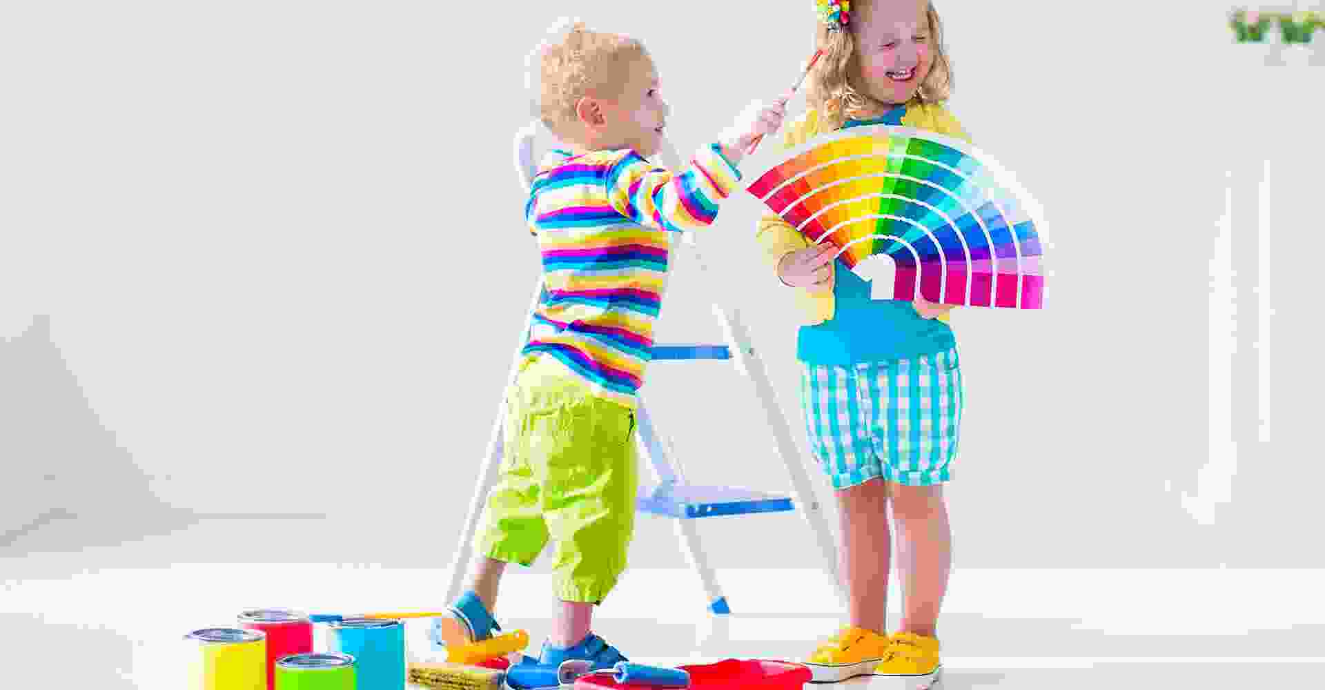Two children playing with paint and paintbrushes in a room.