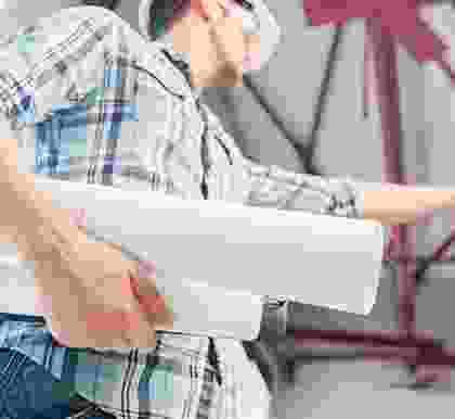 A worker carrying two rolls of paper