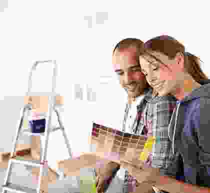 A man and woman looking at paint samples in a room.
