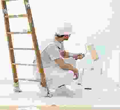 A man painting a room with a ladder.