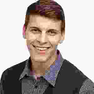 A smiling man wearing a vest and shirt.