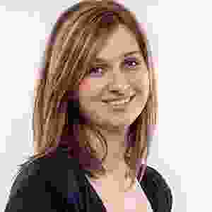 A woman smiling for the camera in front of a white background.