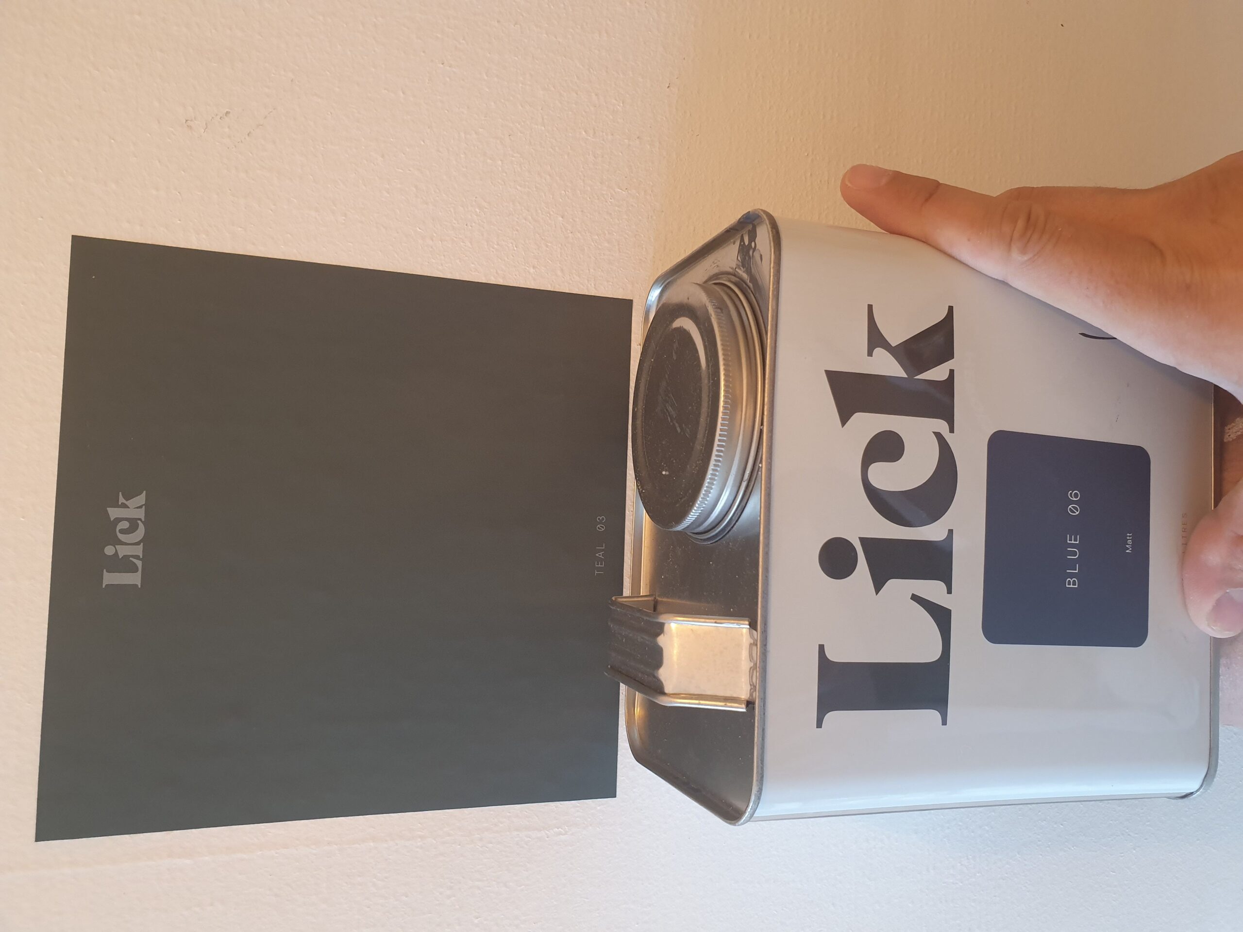 A person holding a can of paint with the word lick on it.