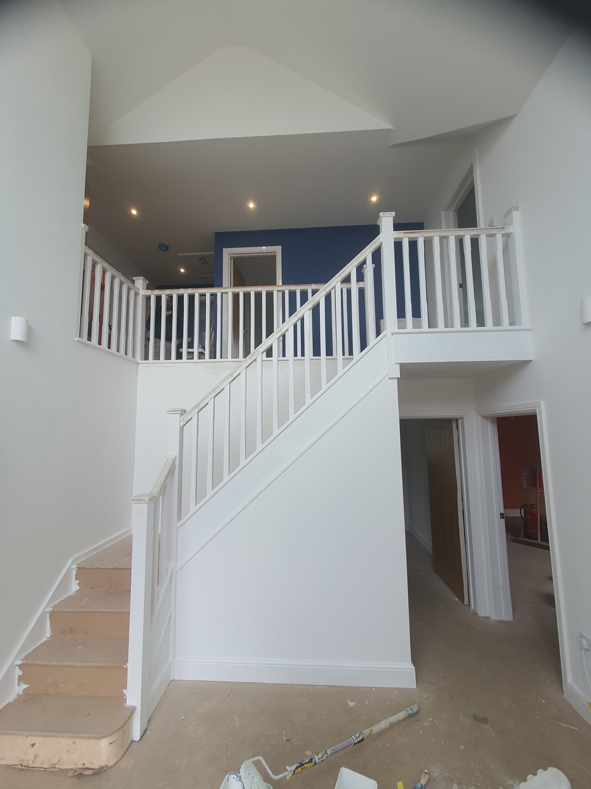 A white staircase with a railing and a blue wall.