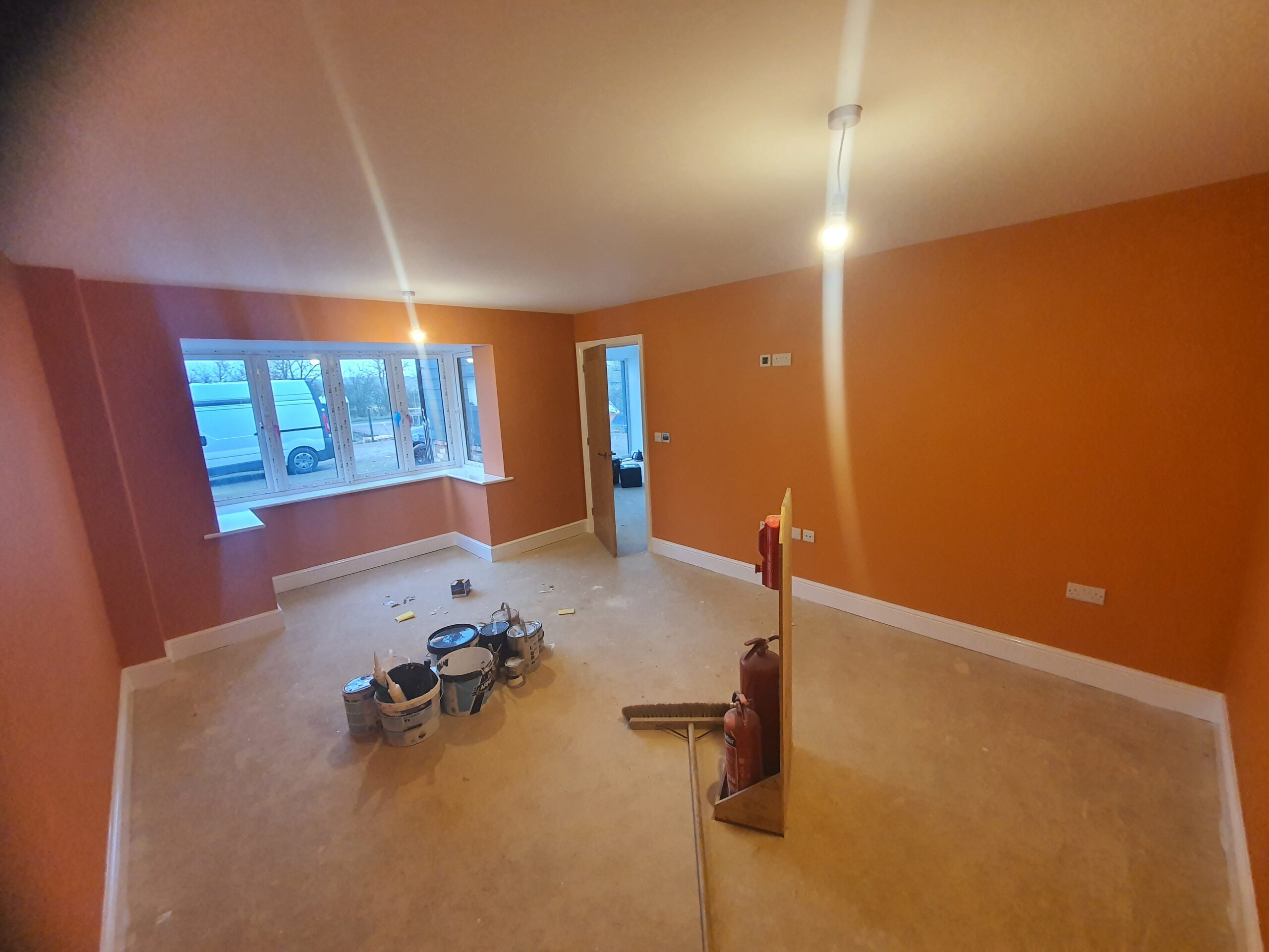 A room with orange walls and white carpet.