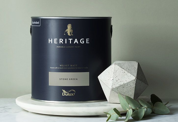 A bucket of heritage paint sits on a table next to an eucalyptus plant.