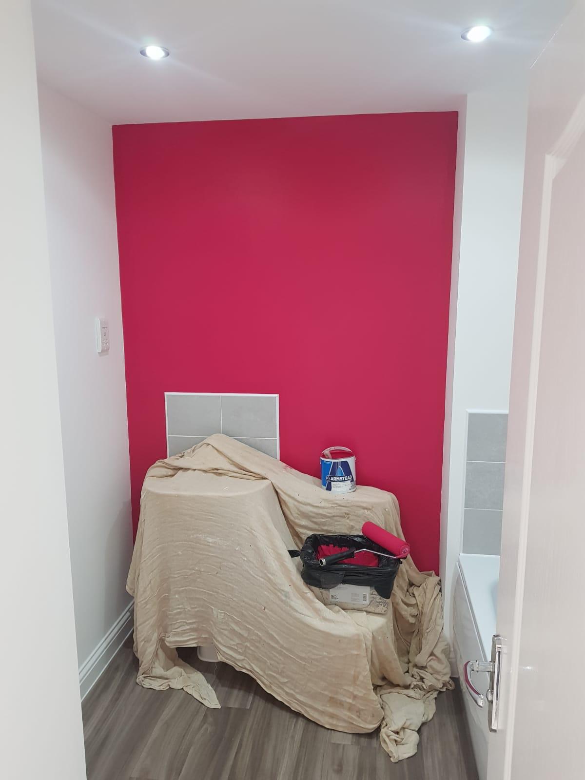 A bathroom with a pink wall and a wooden floor.