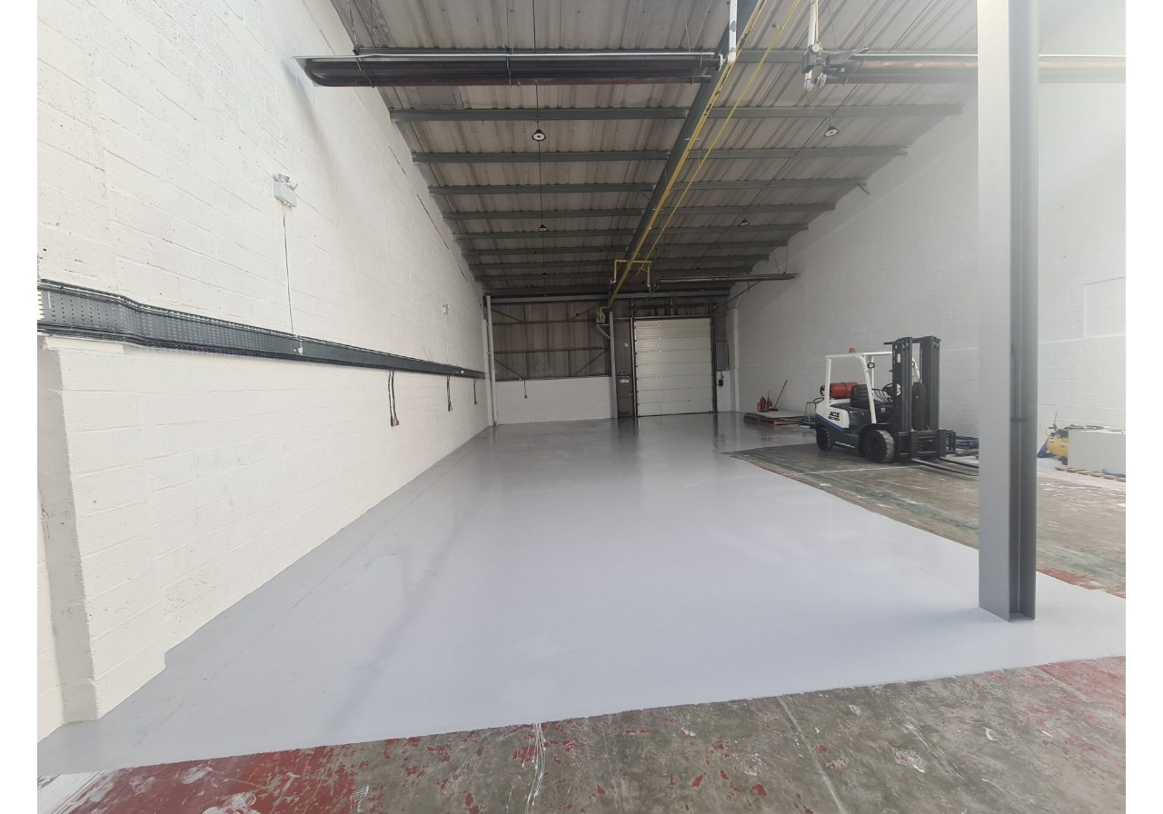 A warehouse with a white floor and a forklift.