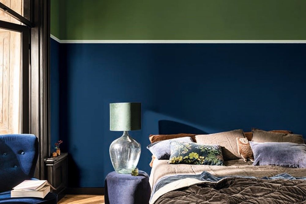 A bedroom with blue walls and green accents.