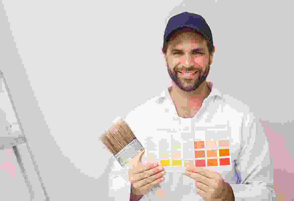 A man holding a paint brush in front of a wall.