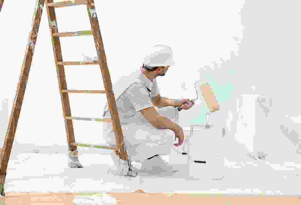 A man painting a room with a ladder.