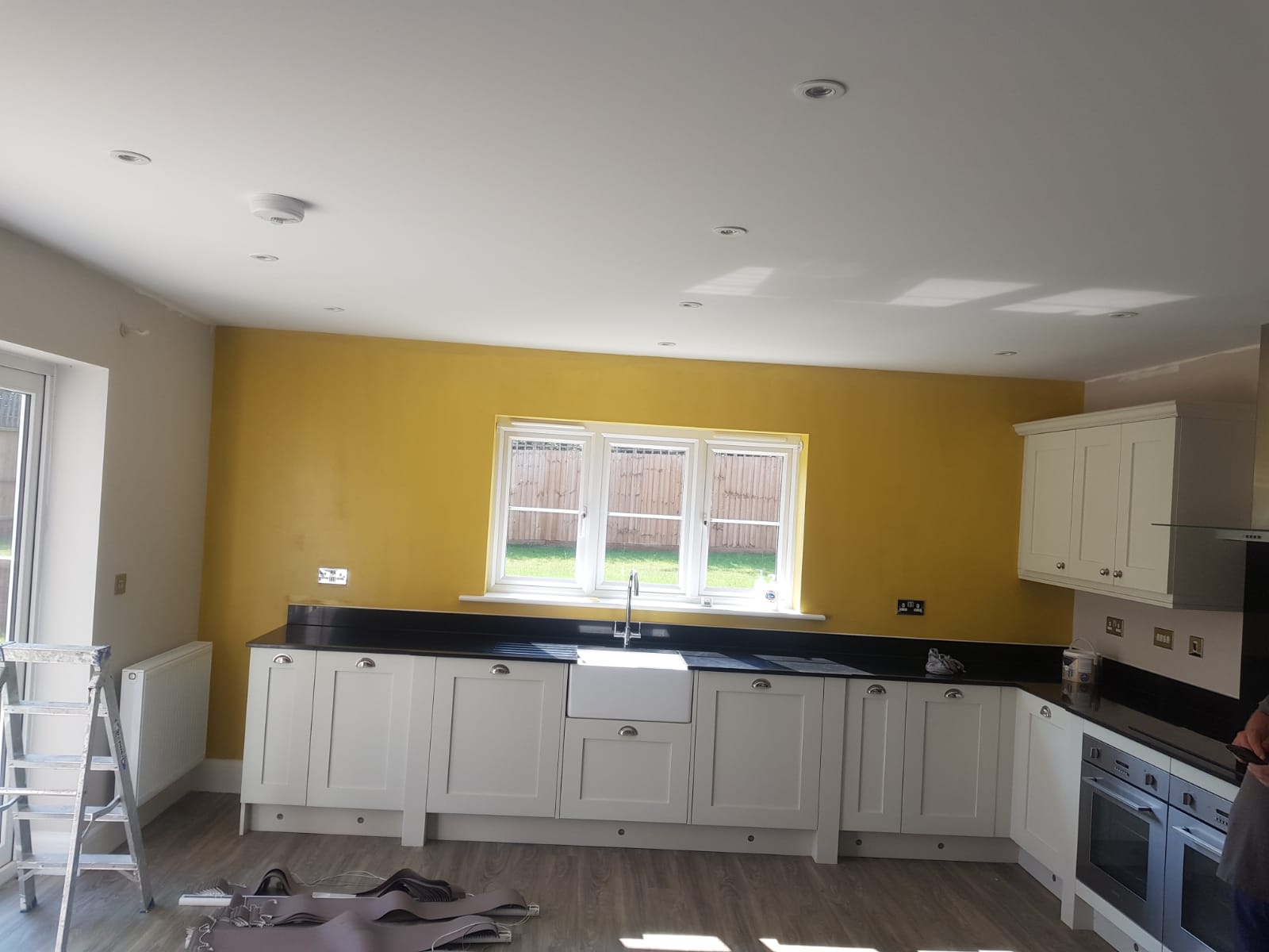 A man is painting a kitchen with yellow walls.