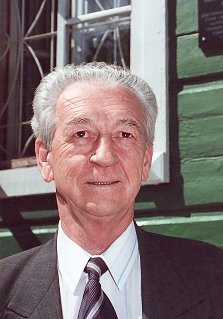 Elderly man in a suit, outdoors.